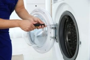 Image depicts a Max Appliance Repair technician repairing a dryer.